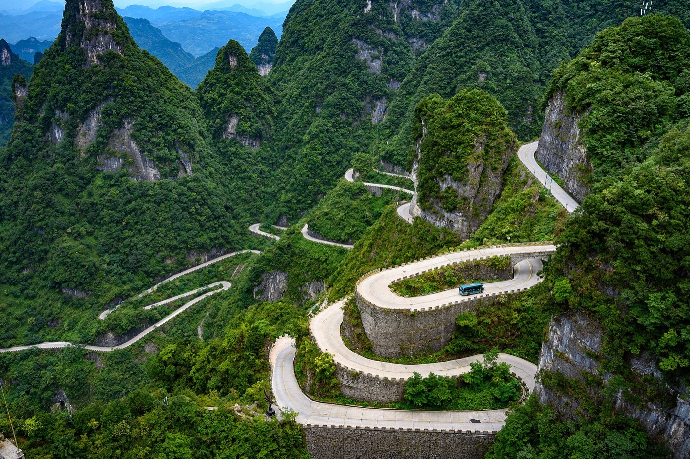 Hairpin bends of Tongtian Avenue winding up Tianmen Mountain, with a shuttle bus on one of the curves