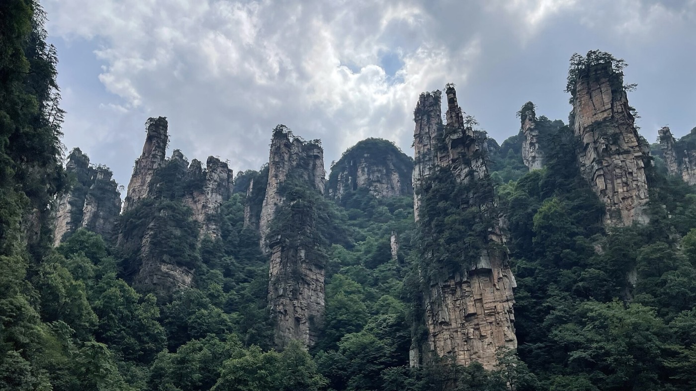 Sandstone pillars of the Wulingyuan Scenic Area seen from below against a partly cloudy sky